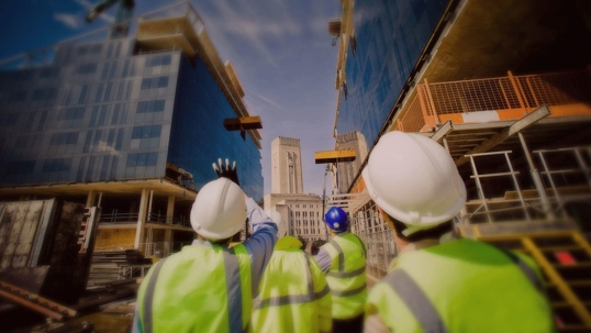 construction workers pointing at top of skyscraper