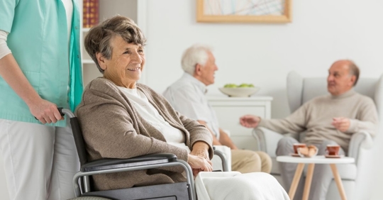 elderly woman being pushed in a wheelchair by nursing home staff