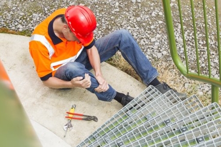 injured construction worker grabbing his leg in pain