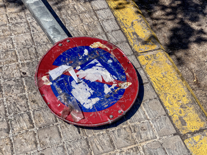 weathered sign laying across sidewalk